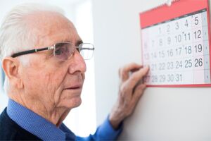 Elderly man who is confused while reading a calendar.