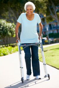 Elderly woman using a walker on a sidewalk