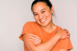 Adult woman hugging herself and smiling.
